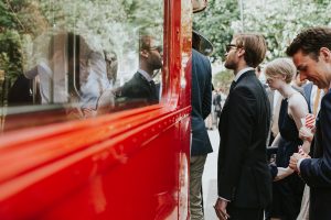 Guest boarding a red bus on a wedding day in London.