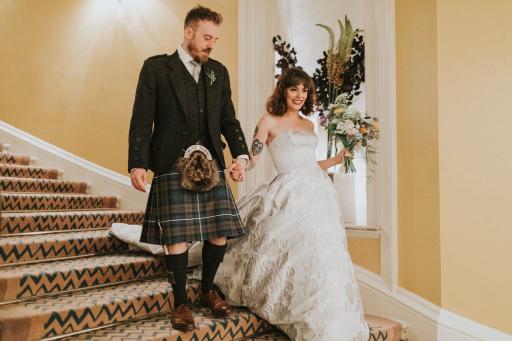 Bride smiling whilst walking down the steps with groom