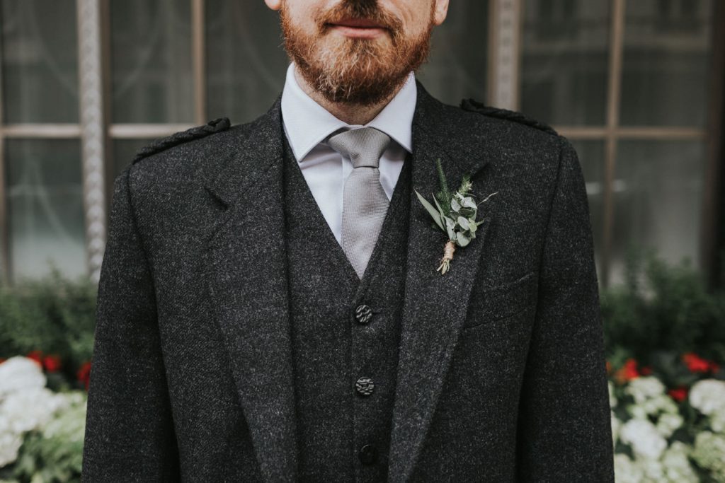 Groom in Wool tailoring and simple button hole flower