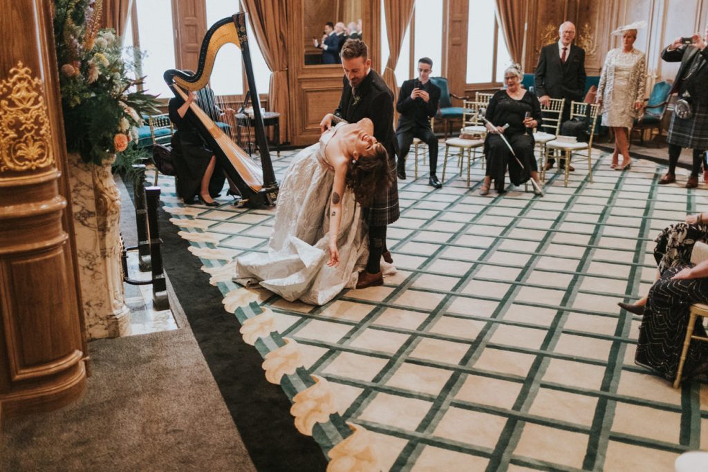 Groom dances with the bride whilst harpist plays music during wedding service