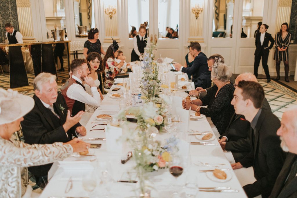 Guests seated on long table with flowers