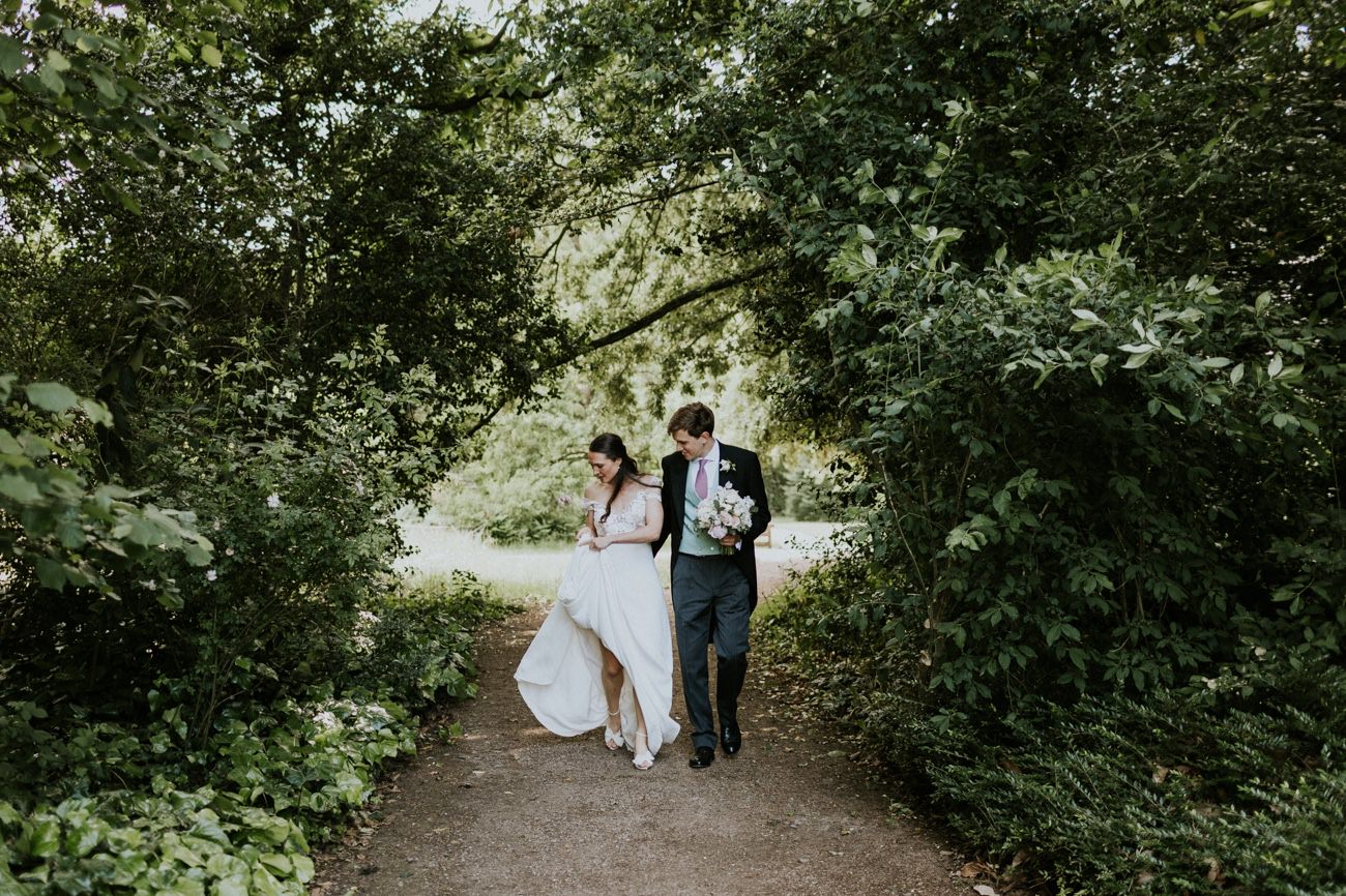 Bride and groom walk through woodland