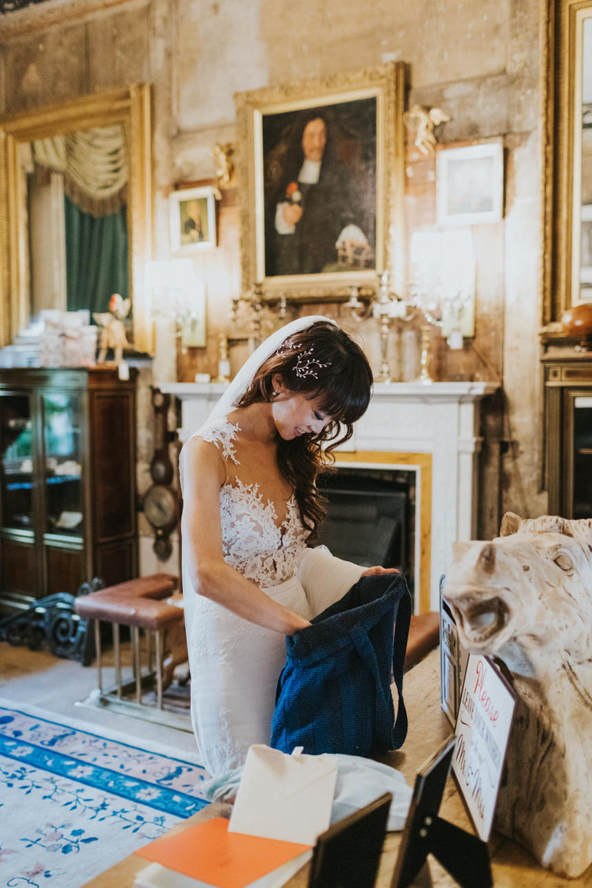 Bride at Brunswick House Wedding venue reaches into a blue bag. Ornate details include a marble fireplace, gilded mirror, and portrait. "Please Leave Mr & Mrs..." sign visible.